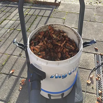 a bucket filled with dirt sitting on top of a sidewalk