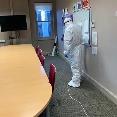 a man in a white suit and protective suit standing in front of a whiteboard