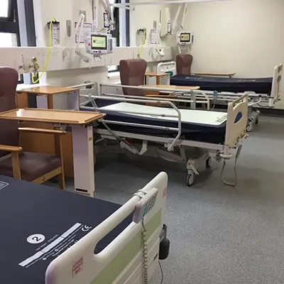 a hospital room filled with lots of beds and chairs