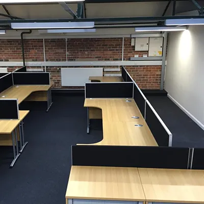 an empty office with desks and a brick wall