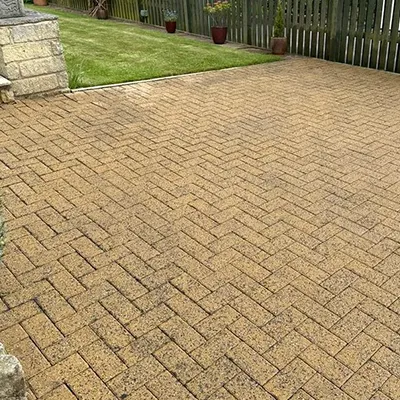a brick patio in a backyard with a fence
